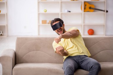 Evde sanal gözlük takan genç bir adam.