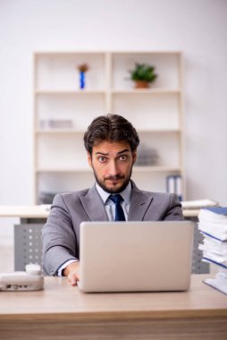 Genç bir erkek çalışan ve ofiste çok fazla iş var.