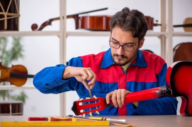 Genç adam atölyede müzik aletlerini tamir ediyor.