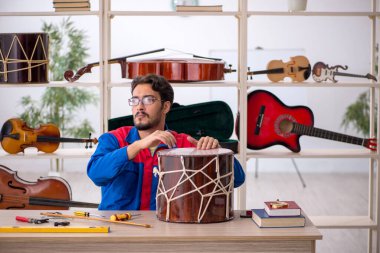 Genç adam atölyede müzik aletlerini tamir ediyor.
