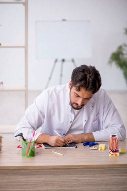Klinikte çalışan genç erkek dişçi.