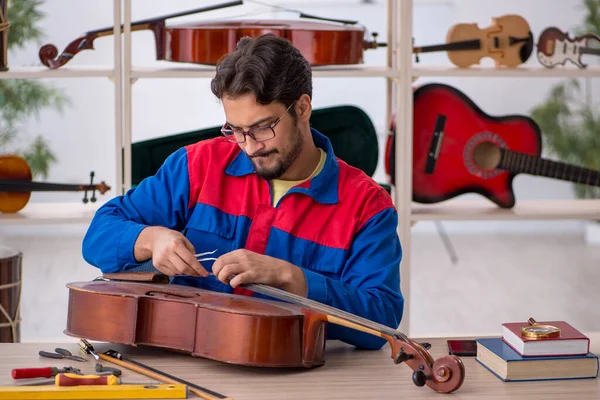 Young man repairing musical instruments at workshop — Stock Photo, Image
