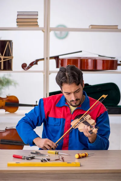 Genç adam atölyede müzik aletlerini tamir ediyor.