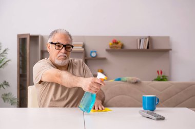 Yaşlı adam evde ev işi yapıyor.