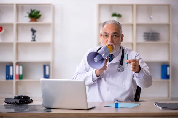 Starý lékař drží megafon na klinice — Stock fotografie