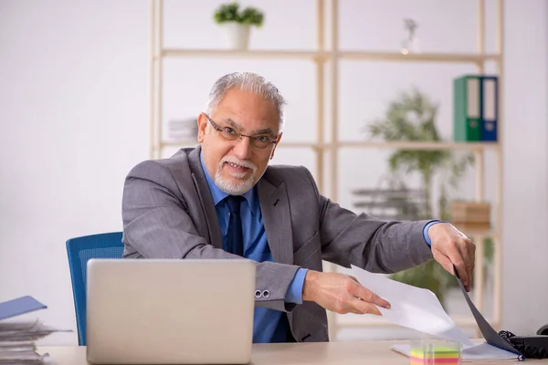 Oude mannelijke werknemer die op de werkplek werkt — Stockfoto