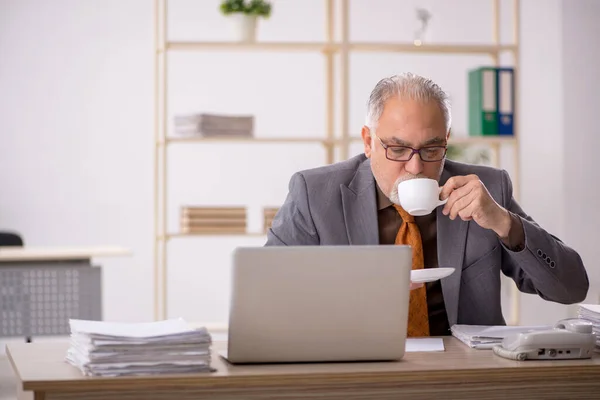 Oude mannelijke werknemer die koffie drinkt tijdens de pauze — Stockfoto