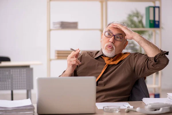 Viejo empleado fumando cigarrillo en el lugar de trabajo — Foto de Stock