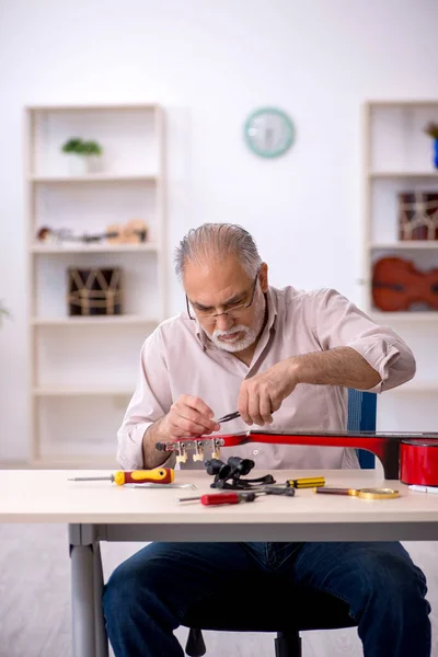 Alter Mann repariert Musikinstrumente in Werkstatt — Stockfoto