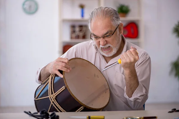 Viejo reparador masculino reparando instrumentos musicales en el taller —  Fotos de Stock