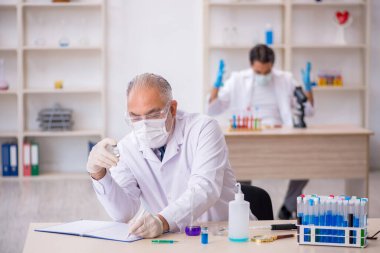 Laboratuvarda çalışan iki erkek kimyager.