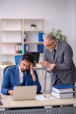 Yaşlı erkek patron ve ofiste çalışan genç erkek çalışan.