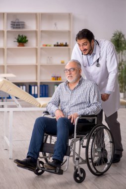 Tekerlekli sandalyedeki yaşlı adam genç erkek doktoru ziyaret ediyor.
