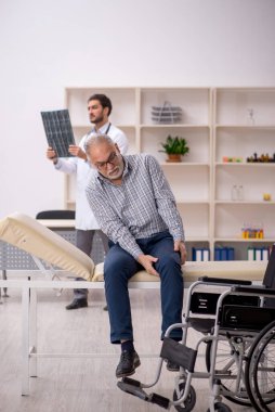 Yaşlı adam genç erkek doktor radyolojisti ziyaret ediyor.