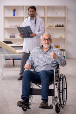 Yaşlı adam genç erkek doktor radyolojisti ziyaret ediyor.