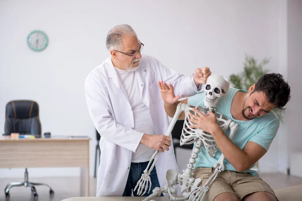 Giovane paziente maschio visita vecchio medico maschio — Foto Stock