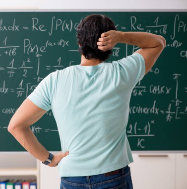 Kara tahta önünde genç erkek öğrenci matematikçi