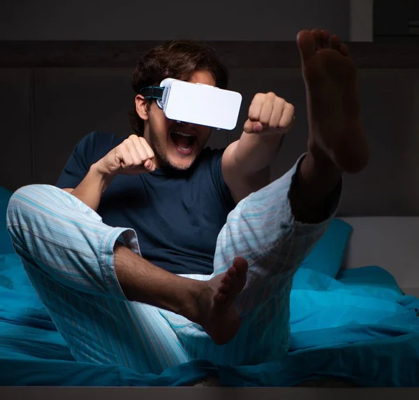 Jovem jogando jogos de computador à noite na cama — Fotografia de Stock