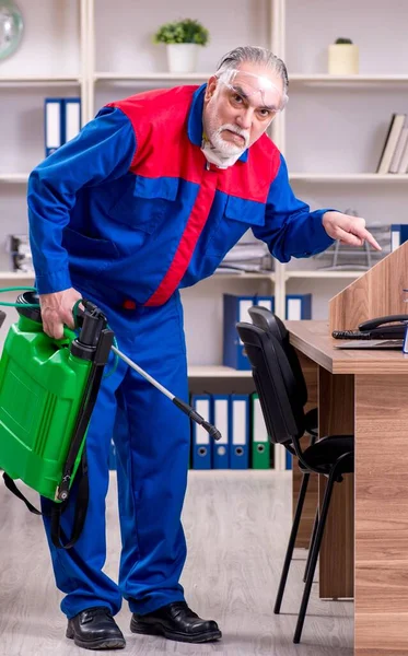Oude professionele aannemer doet ongediertebestrijding in het kantoor — Stockfoto