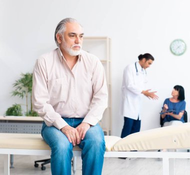 Yaşlı çift genç erkek doktoru ziyaret ediyor.