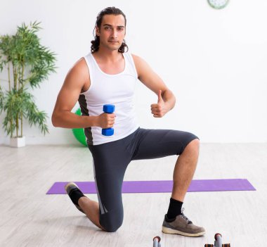 Genç yakışıklı adam içeride spor yapıyor.