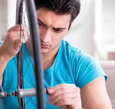 Evde bisiklet tamir eden genç bir adam.