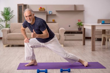 Yaşlı adam içeride spor egzersizleri yapıyor.