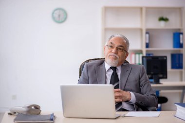 İş yerinde oturan yaşlı erkek çalışan.