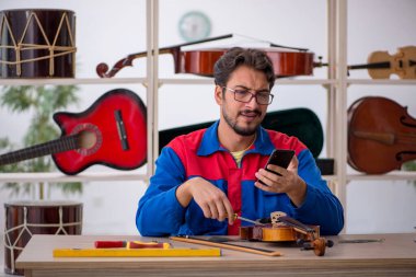 İçeride müzik aletlerini tamir eden genç bir adam.