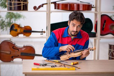 İçeride müzik aletlerini tamir eden genç bir adam.