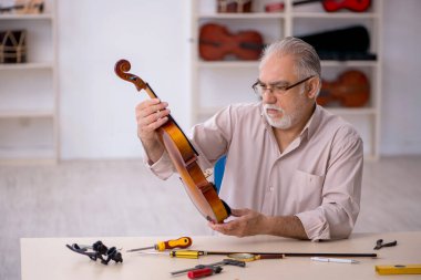 Eski tamirci atölyede müzik aletlerini tamir ediyor.