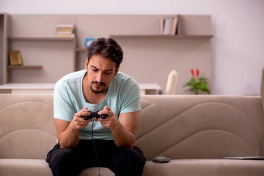 Evde oyun oynayan genç bir erkek öğrenci.