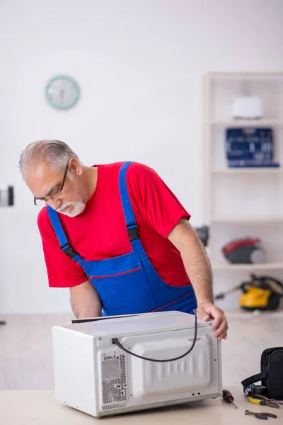 Oude Mannelijke Reparateur Repareert Oven Werkplaats — Stockfoto