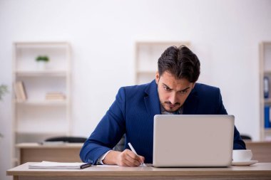 Genç işadamı işyerinde oturuyor.