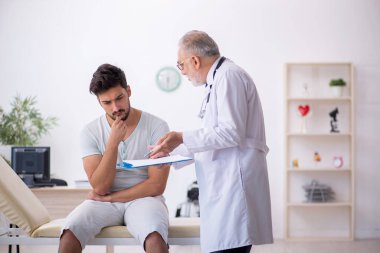 Genç hasta yaşlı erkek doktoru ziyaret ediyor.