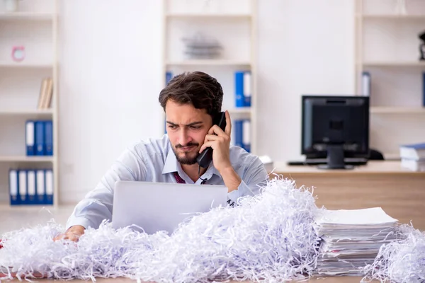 Young businessman employee and a lot of cut papers in the office