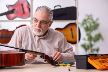 İş yerinde müzik aletlerini tamir eden eski bir tamirci.