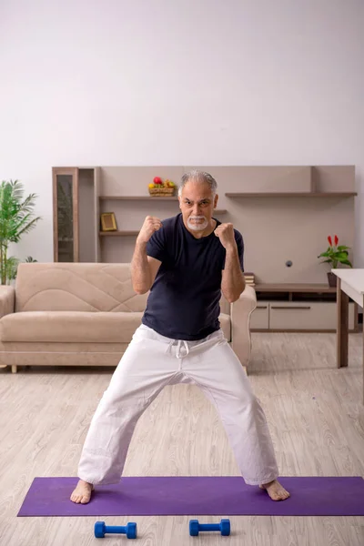 Old man doing sport exercises indoors