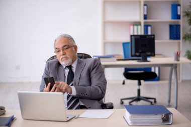 İş yerinde oturan yaşlı erkek çalışan.
