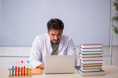 Genç kimyacı öğretmen beyaz tahtanın önünde.