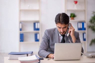 Genç işadamı işyerinde oturuyor.