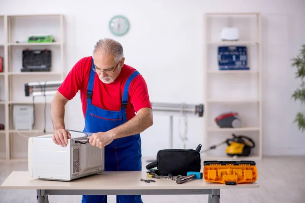 作業場でオーブンを修理古い男性修理人 — ストック写真