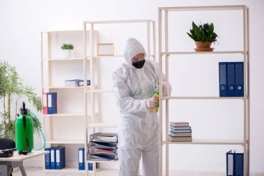 Young contractor disinfecting office during pandemic