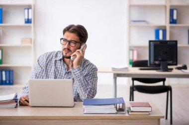 Genç erkek çalışan işyerinde oturuyor.