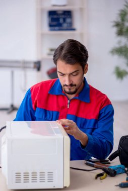 Atölyede fırın tamir eden genç bir tamirci.