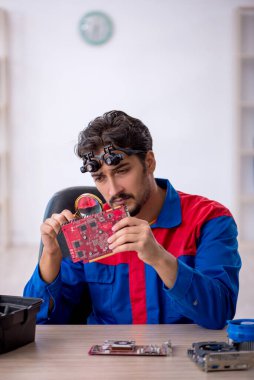 Atölyede bilgisayar tamir eden genç bir tamirci.