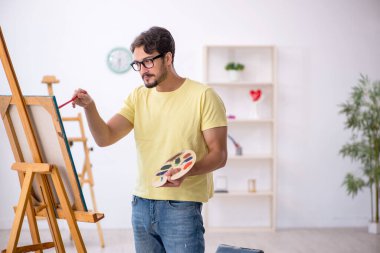 Genç erkek ressam evde resim yapmaktan hoşlanıyor.