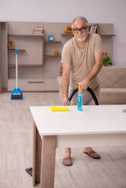 Evde ev işi yapan yaşlı bir adam.