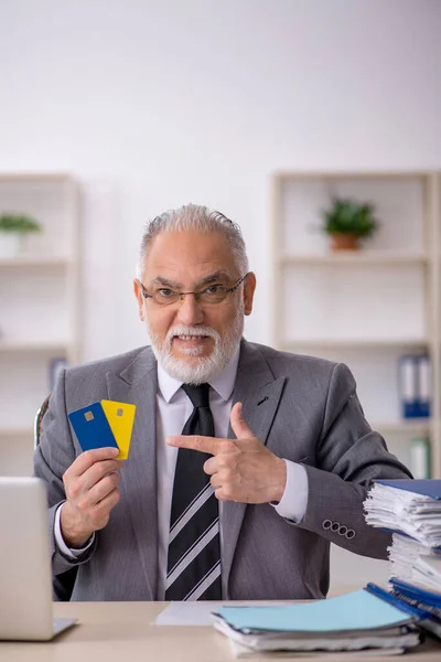 Old businessman employee holding credit card in the office