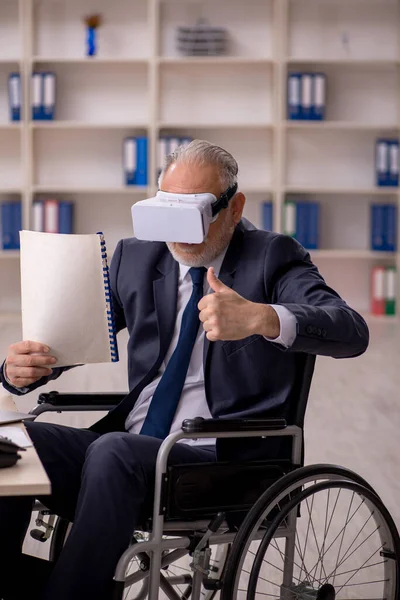Old leg injured businessman employee wearing virtual glasses in the office